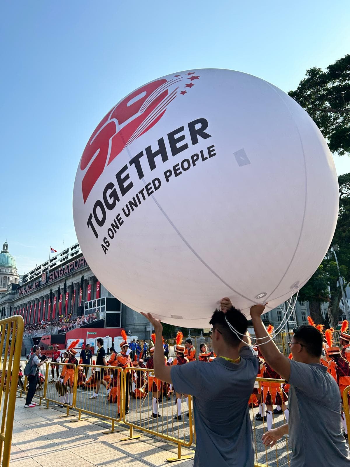 印有 Together as One United People 字样的 SG59 巨型球体,由工作人员在新加坡国庆巡游中托举