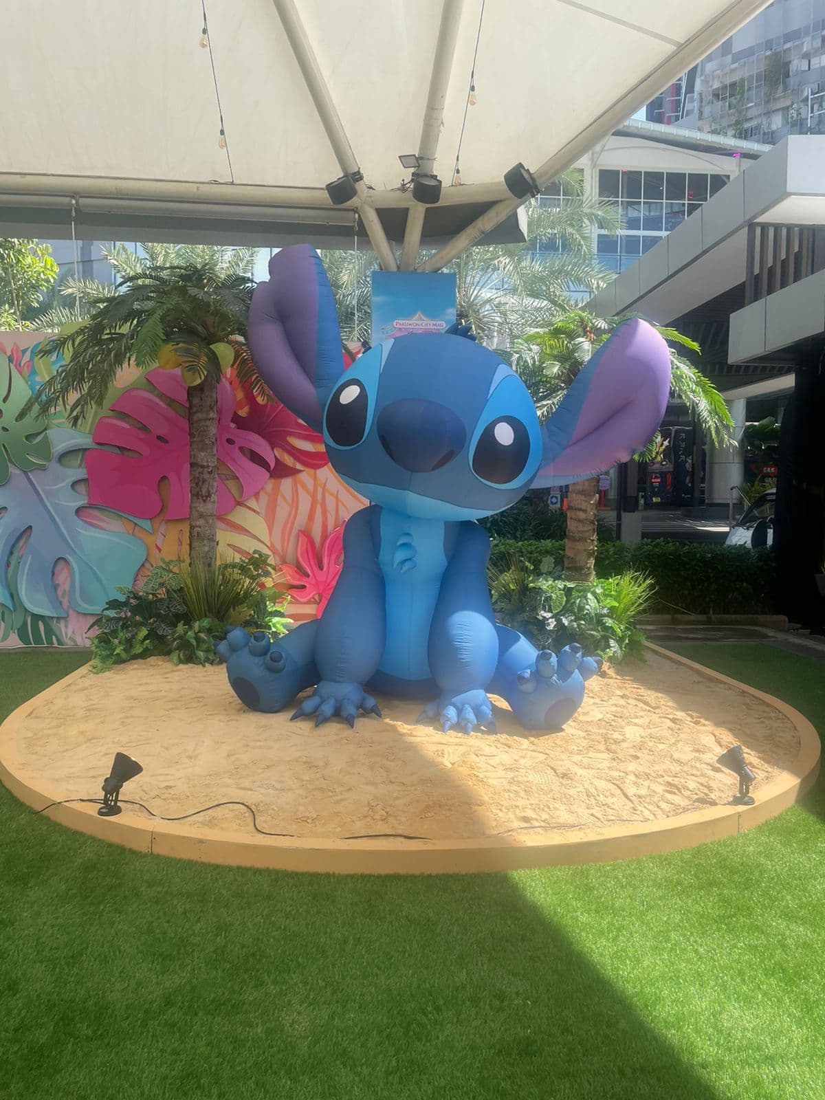 印尼 Pakuwon City Mall 内,一尊大型坐姿 Stitch 充气装置置于沙景展台上