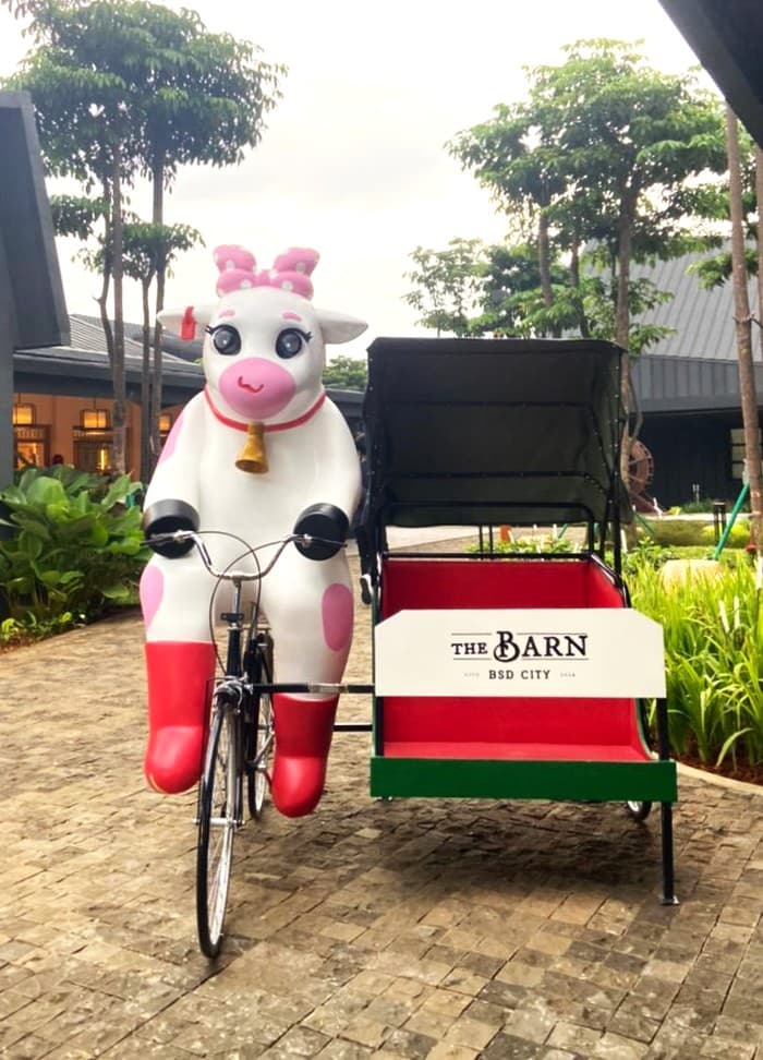 印尼 BSD City 的 The Barn 门外,一尊粉白色奶牛骑三轮车的雕像